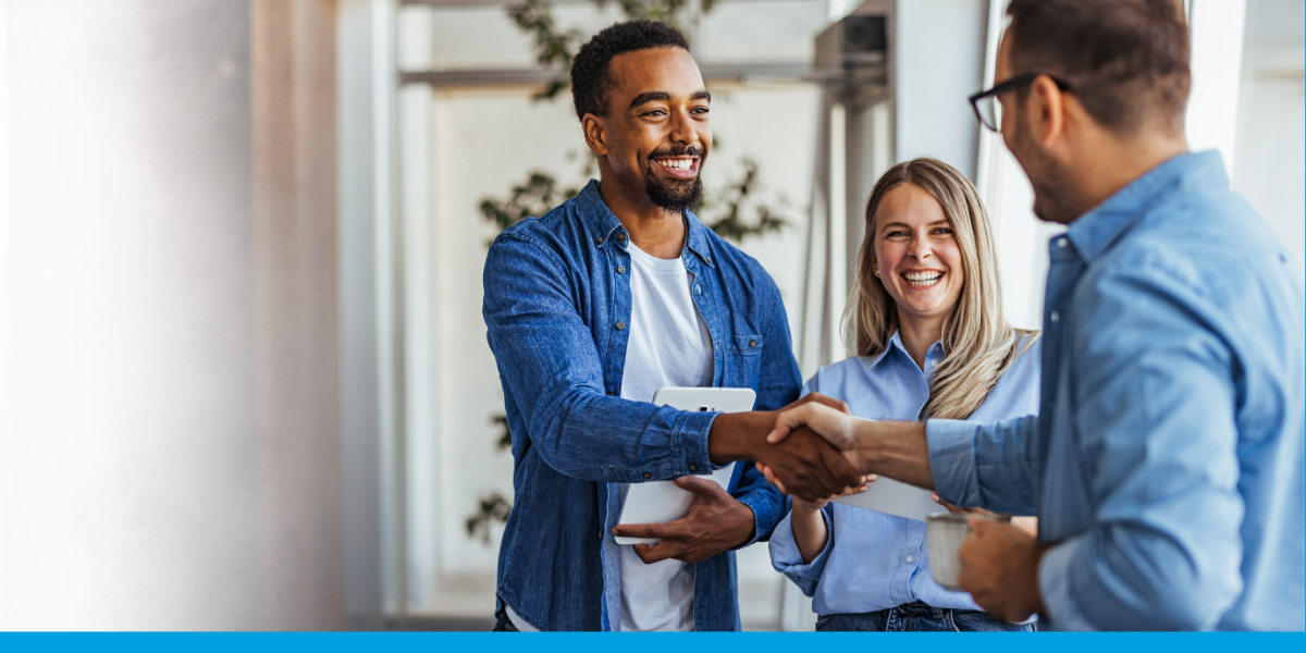 drie jonge professionals die lachend kennis maken en handen schudden